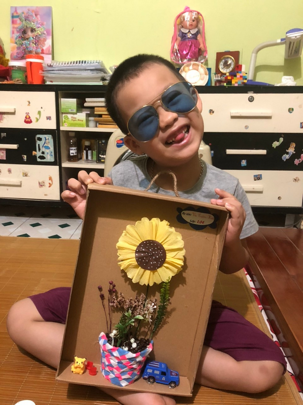 A child holding a flower in a box

Description automatically generated