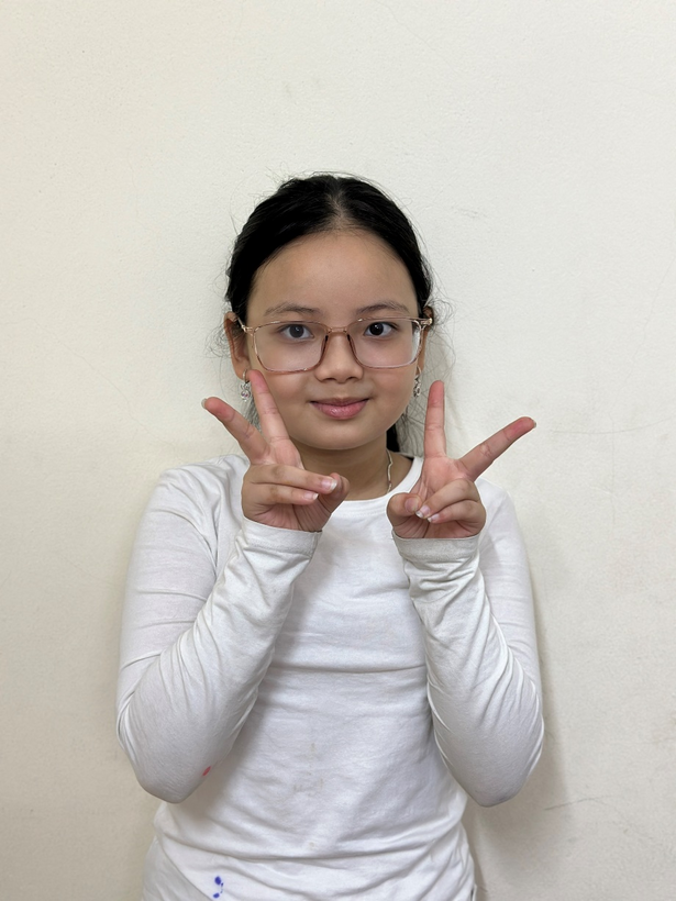 A child with glasses making a peace sign

Description automatically generated